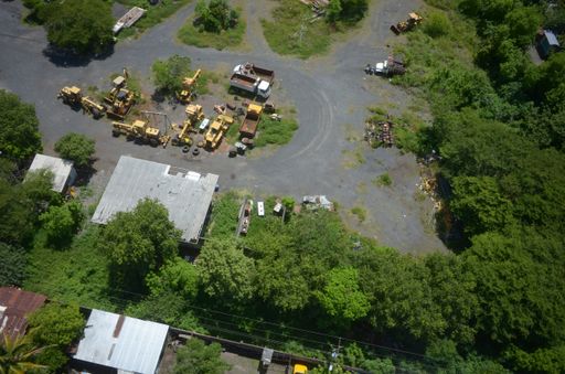 A high angle aerial photography shot of some trucks working in an area with trees