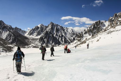 A scenic view of people climbing the snowy mountains in winter on a sunny day