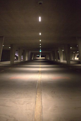 A vertical shot of an empty parking lot with overhead lights