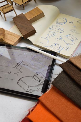 A vertical closeup of a sketchbook and a tablet. Concept of furniture design.
