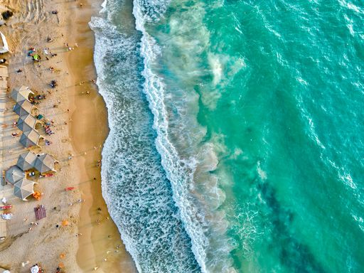 An aerial view of the vacationers on a sandy beach with clear turquoise water