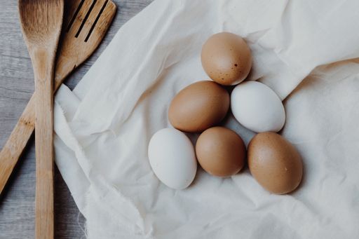 A high angle top view closeup shot of white and brown eggs in a napkin on a wooden table