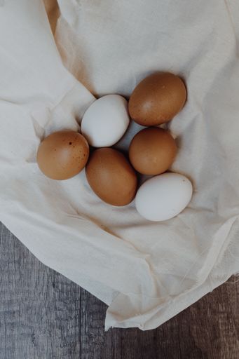 A vertical high angle top view closeup shot of white and brown eggs in a napkin on a wooden table