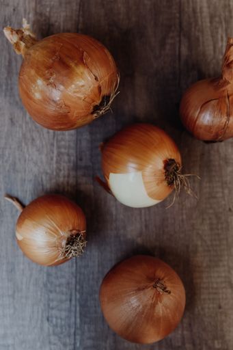 A vertical top view closeup shot of white onions on a wooden table