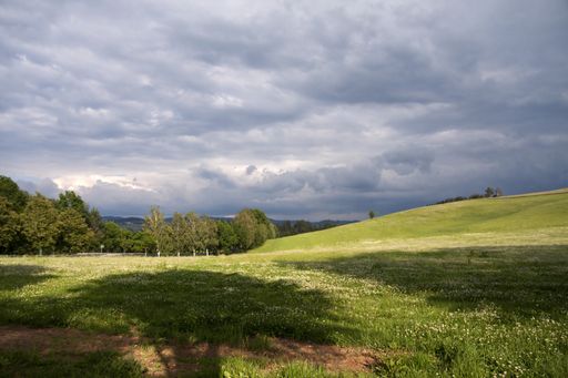 A breathtaking shot of a field surrounded by hills under the cloudy sky