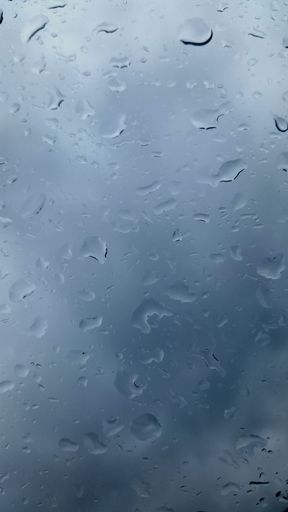 A vertical closeup shot of raindrops on a glass - perfect for a rainy background