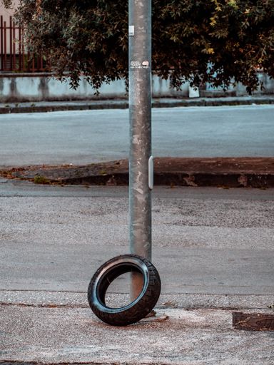 A vertical shot of an old tire near a rusty metal pole in Naples, Italy