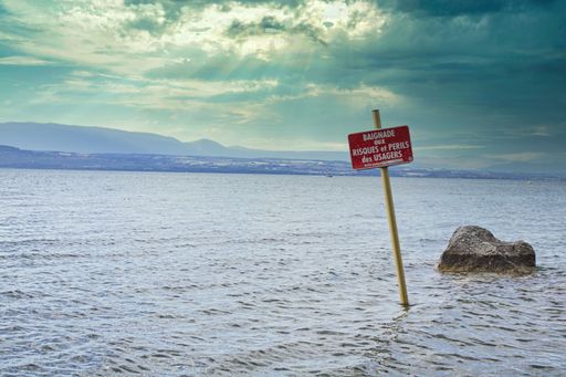 A sign board in the lake saying Swim at your own risk in the lake Geneva, France-Switzerland
