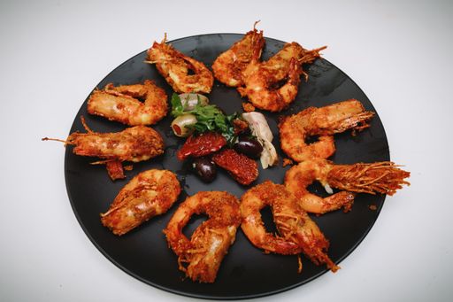 A high angle closeup shot of fried prawns on a round black tray
