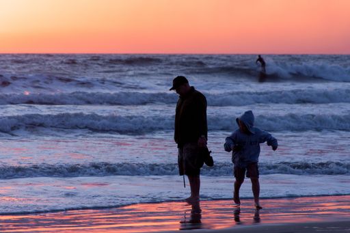 A beautiful shot of a scenic sunset at Pacific Beach with orange skyscape and people enjoying the beach