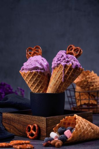 A vertical shot of two ice cream in waffle cone