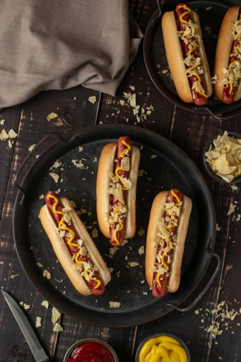 A view of hot dogs with ketchup and mustard sauce served on a black plate