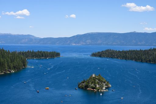 A high angle shot of an islet isolated in the ocean surrounded by fir tree islands and high rocky mountains