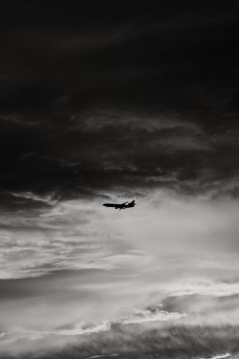 A vertical grayscale shot of an airplane flying on an aesthetic cloudscape background in Seattle, WA
