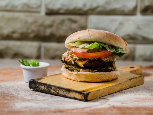 A closeup of a double cheeseburger served on a wooden tray