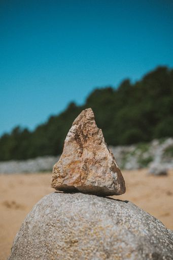 A selective focus shot of a triangular rock set on another one in a desert area