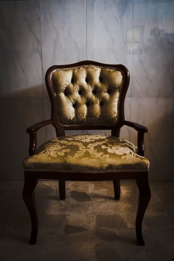 A vertical shot of a vintage chair in a room under the lights