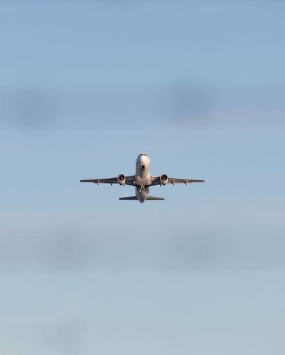 A vertical shot of an airplane taking off with the blue clear sky in the background
