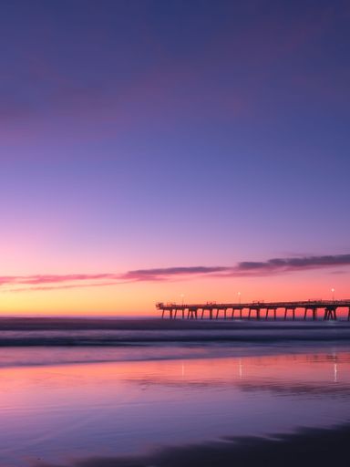 A vertical shot of a beautiful sunset over the ocean with pink clouds in the sky