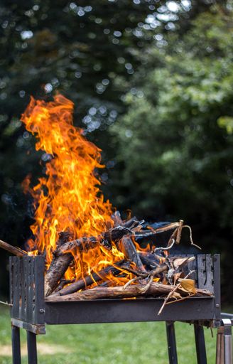 A vertical focus shot of burning wood in a fire pit outdoors