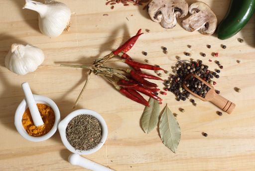 Herbs and Spices on Rustic Table With Jars of Red and Brown Rice in Background Shallow DOF