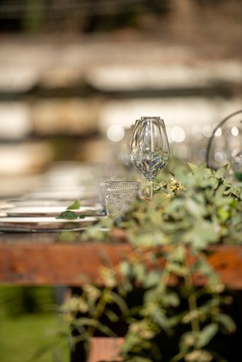 A vertical selective focus shot of empty glasses and plates on a table at a wedding party with blurred background