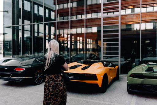 Woman standing looking at exotic supercars.