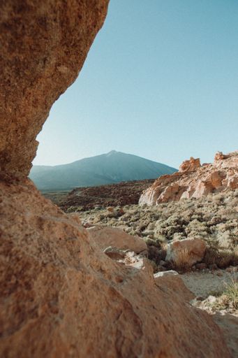 A vertical shot of a rocky hill under a clear blue sky