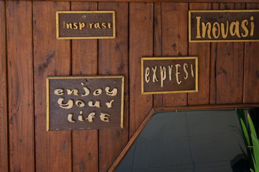 Wooden wall posters saying inspiration, innovation, expression in Indonesian and Enjoy your life in English