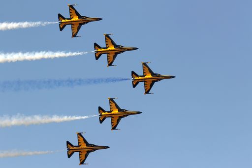 A low angle shot of yellow jets maneuvering in the sky during an air parade