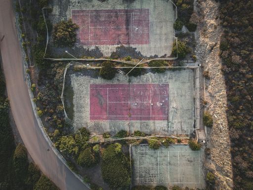 A top view shot of three abandoned tennis courts next to each other