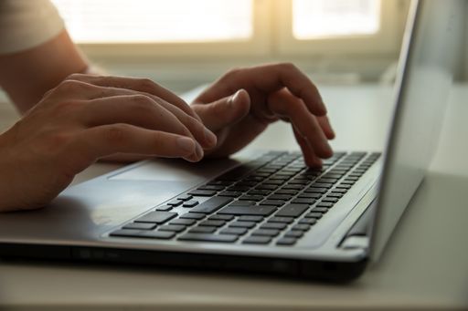 A closeup shot of male hands working with a laptop