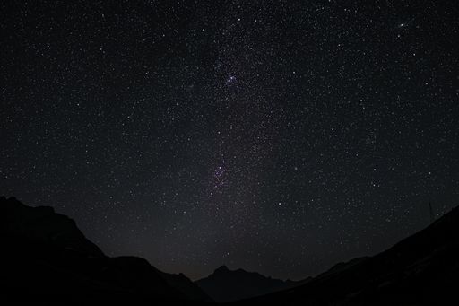 A lovely view of a bright sky with glowing stars and galaxies over a field at night