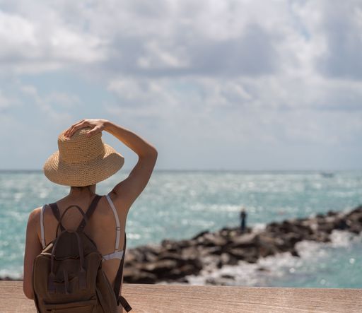 A closeup of a girl with a straw hat looking at the sea.