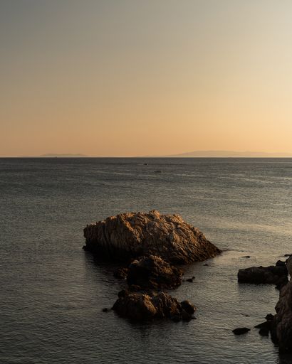 A vertical shot of rocks of different sizes in the sea under the clear sky
