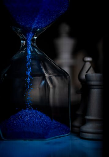 A vertical shot of a blue sand timer with blurred background
