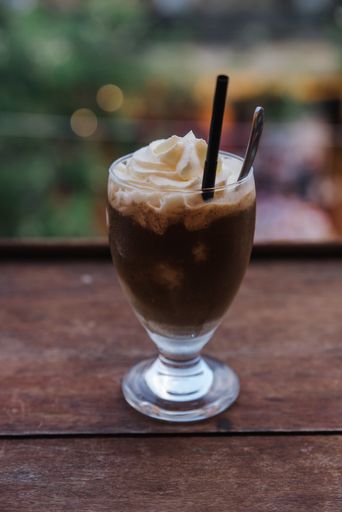 A vertical shot of iced coffee with whipped cream on top
