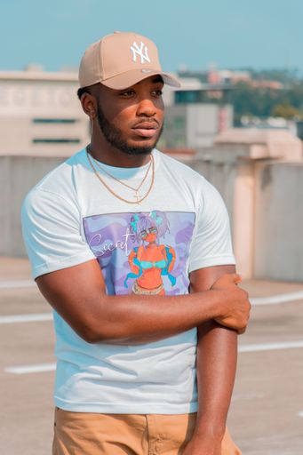 A portrait of an African-American male wearing casual clothes and a cap standing on a rooftop