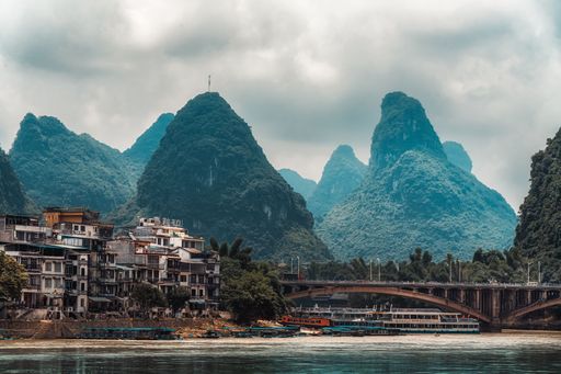 A cityscape of Guilin in China, with a beautiful view of forested Guilin's mountain in the background on a cloudy day