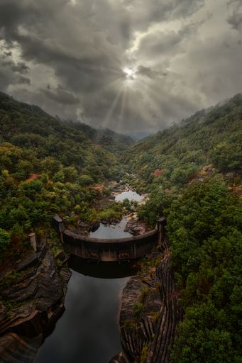 An aerial view of river surrounded by dense trees and mountains