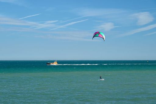 A kite surfer in the turquoise sea in Ramsgate with a pilot boat in the background