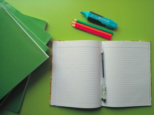 An open book on a green table with big books and stationery