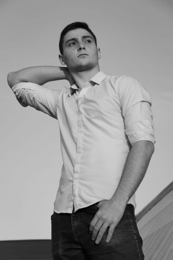 A grayscale of a handsome male in a casual outfit looking side, vertical shot