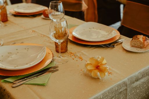 A table set in a restaurant with plates, silverware, wine glasses and napkins