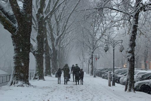 A beautiful shot of people walking along the sidewalks leaving traces on the snow during snowfall