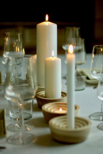 A vertical selective focus shot of a  dinner table with lit candles near wine glasses with a blurred background