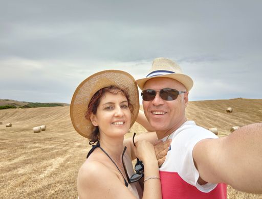 A young female with a sunhat and her husband in a hat and sunglasses taking a selfie on a field