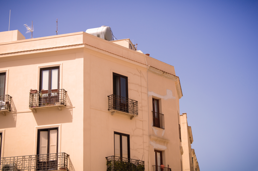A building with a yellow facade with small balconies with beautiful railings