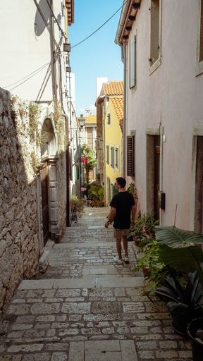 A vertical shot of a young male tourist walking around the streets of Rovinj, Croatia