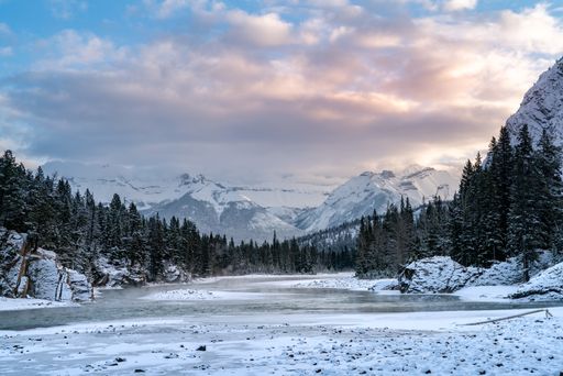 A beautiful shot of a mountainous area covered with snow and surrounded by forests